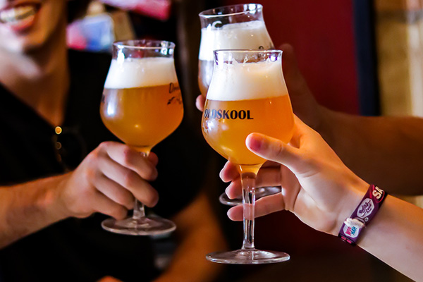 Three guests raising glasses of Oldskool beer at Drinkers Pub